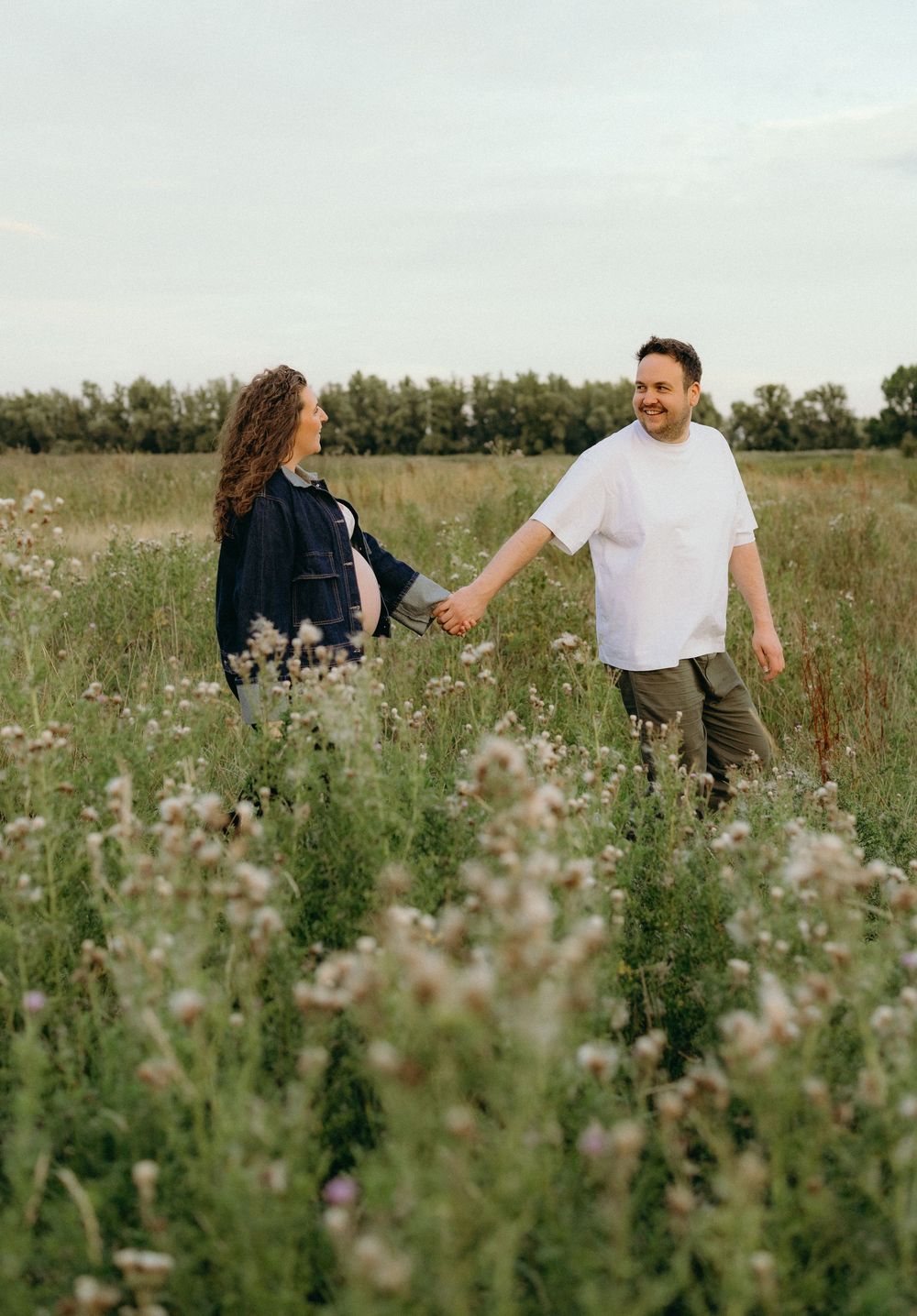 Couple walking through a wildflower meadow on a sunny day.