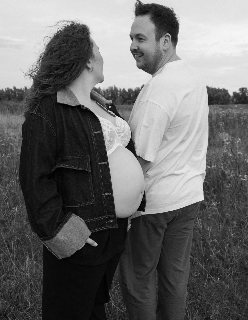 Couple sharing laughter in a field of tall grass and wildflowers.