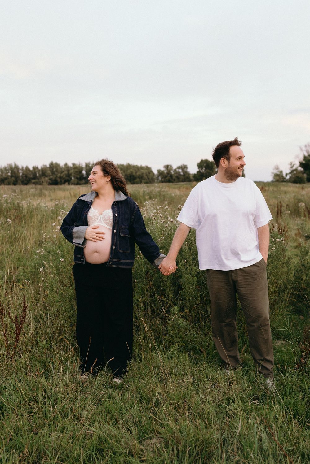 Couple standing together in a grassy field during a romantic outdoor photoshoot.