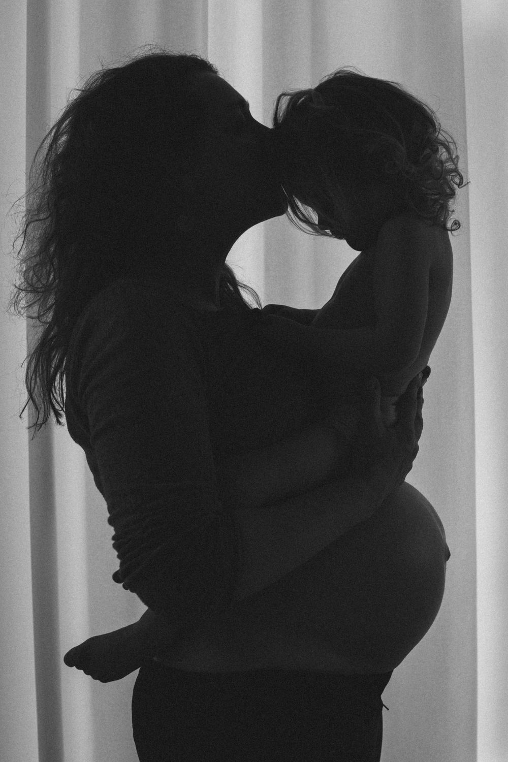 Silhouetted figures in an artistic black and white photo series against backlit curtains.