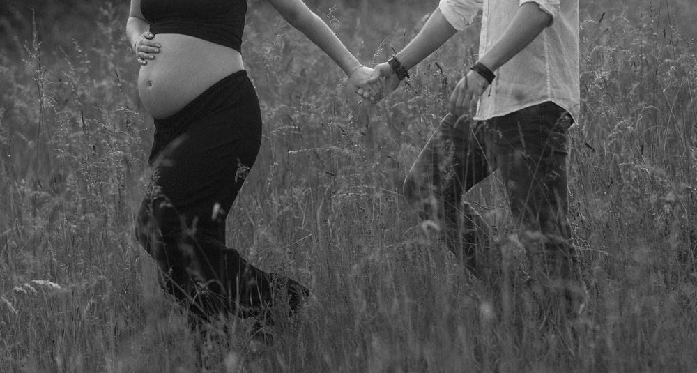 Couple spins gracefully through tall grass in a natural outdoor setting.