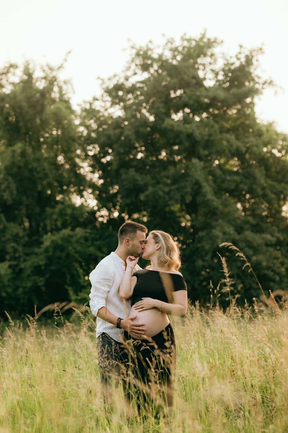 Couple shares a tender moment in a sun-drenched field of wild grass.