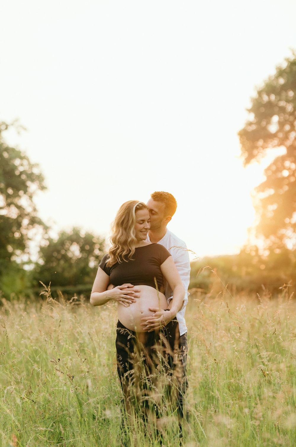 Intimate maternity photos taken in a golden field at sunset.