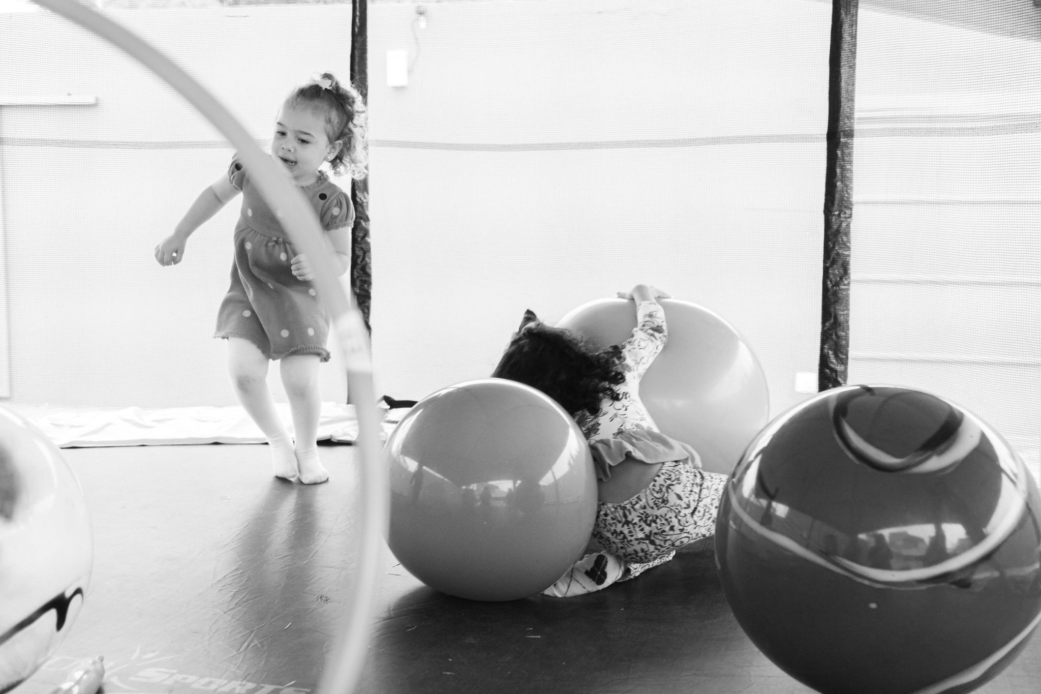 Three exercise fitness balls in different sizes lined up next to each other against a white wall.