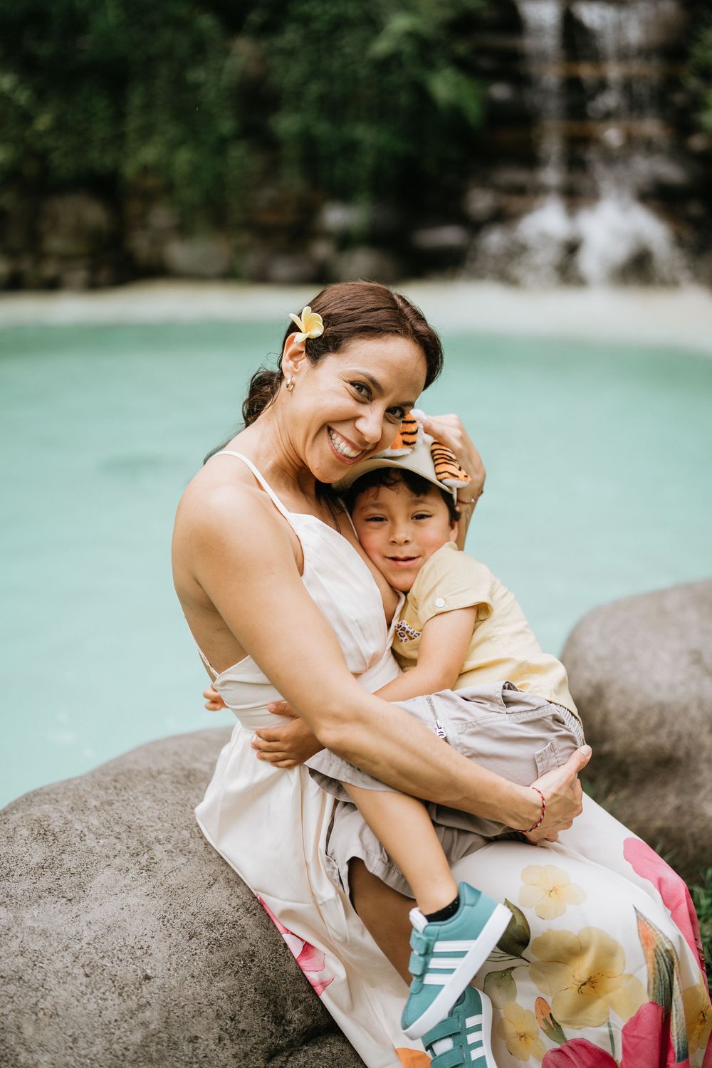 Two people share an intimate moment while sitting on rocks near turquoise water.