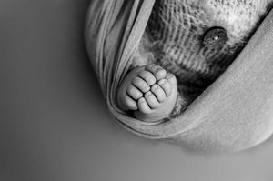 Close-up black and white photo of tiny baby feet wrapped in a cozy blanket.
