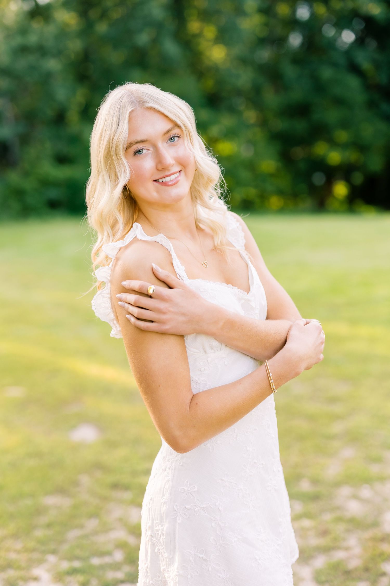 Candid portrait series in white summery dress with bright natural lighting and green foliage background.