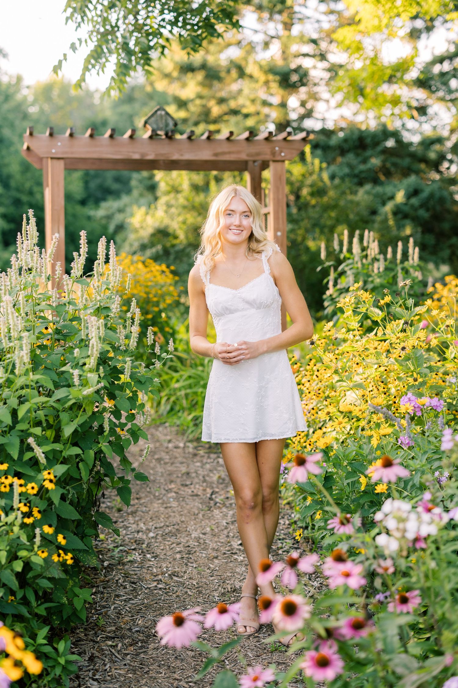 A walking path through a summer garden bordered with vibrant pink echinacea and yellow black-eyed susan flowers.