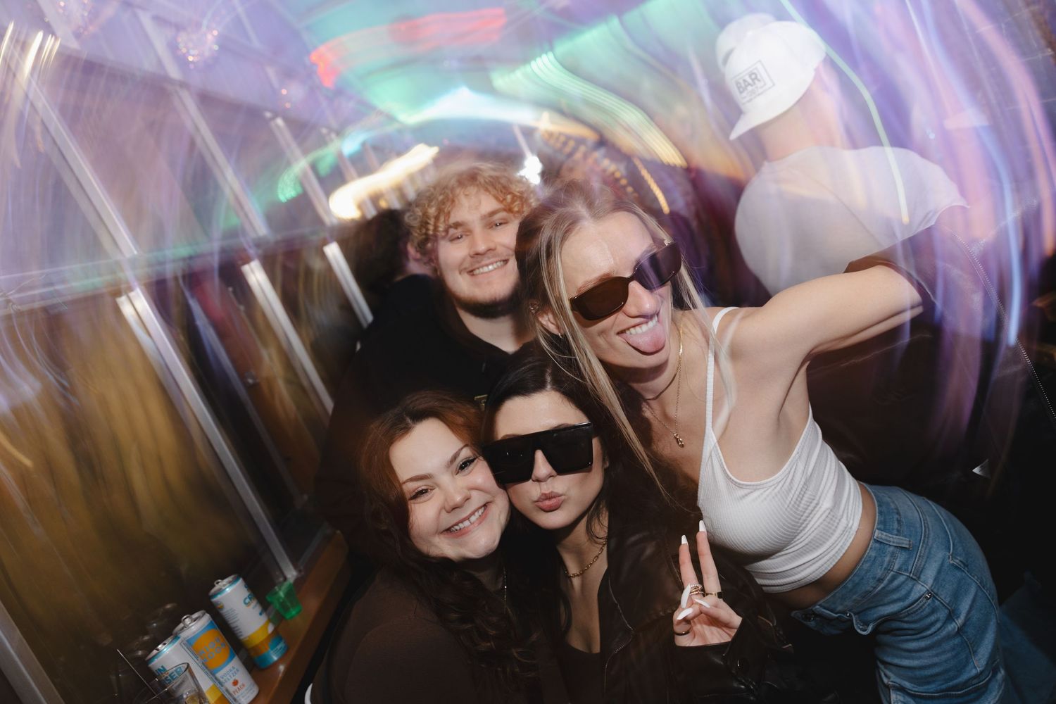 Group of people dancing and having fun at a nightclub with colorful lights and party atmosphere.