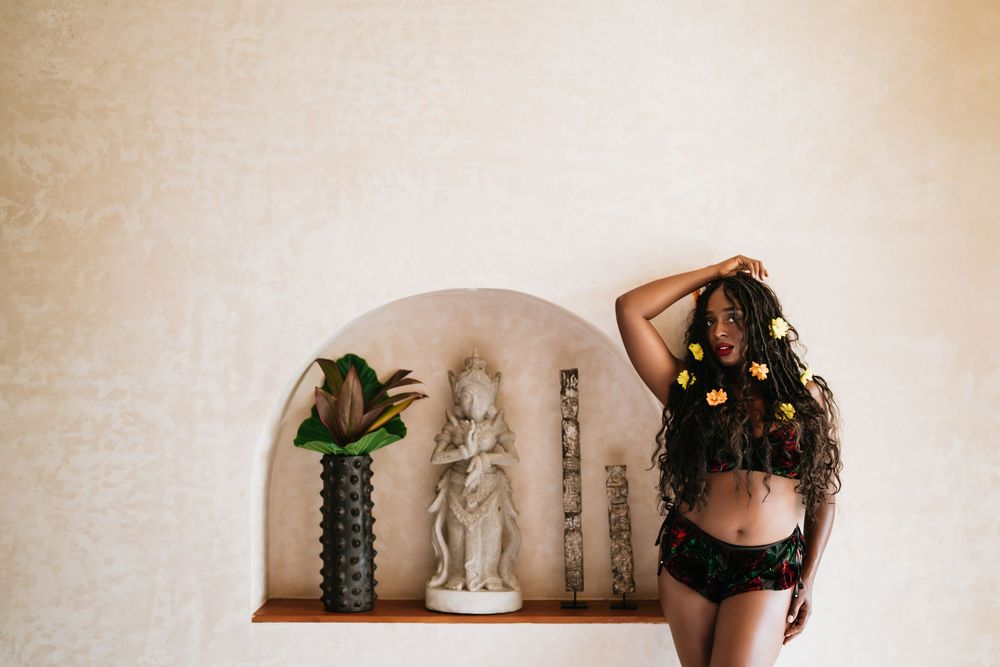 Artistic boudoir photo with decorative alcove and indoor plants creating bohemian atmosphere.