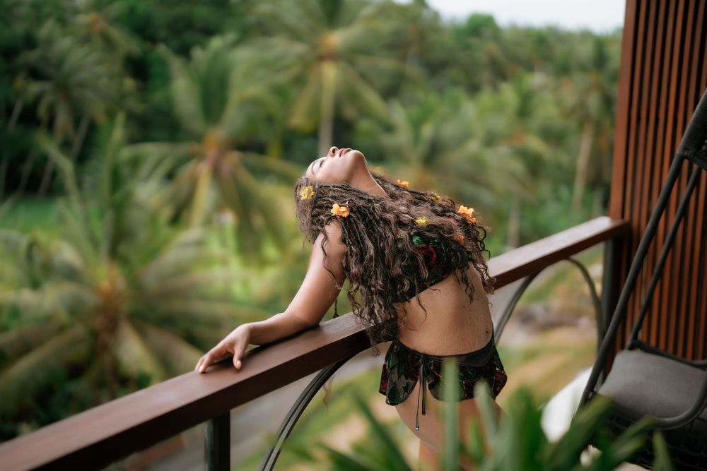 Artistic pose on balcony overlooking tropical palm tree landscape.