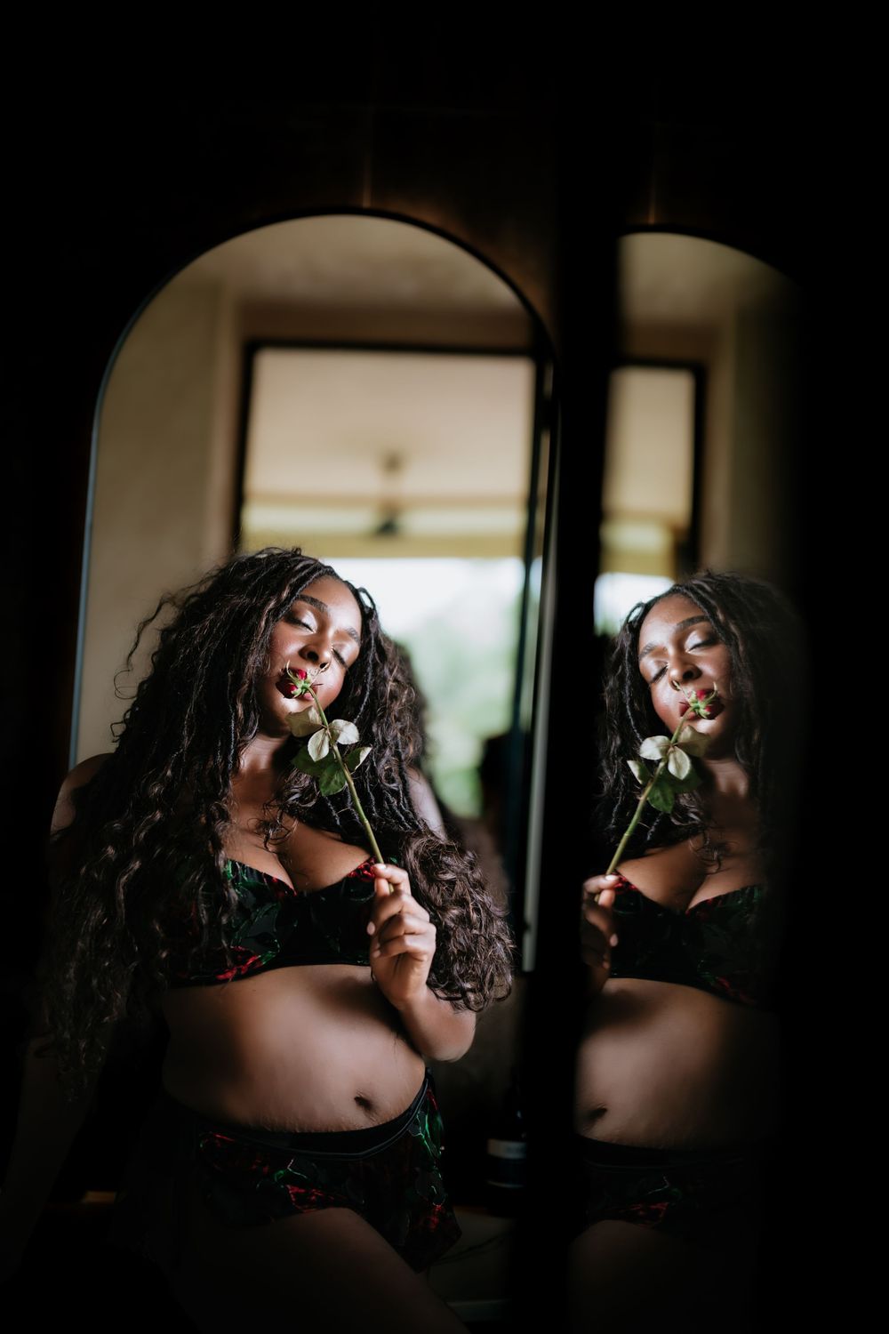 Moody boudoir photography series with dramatic lighting and floral elements.