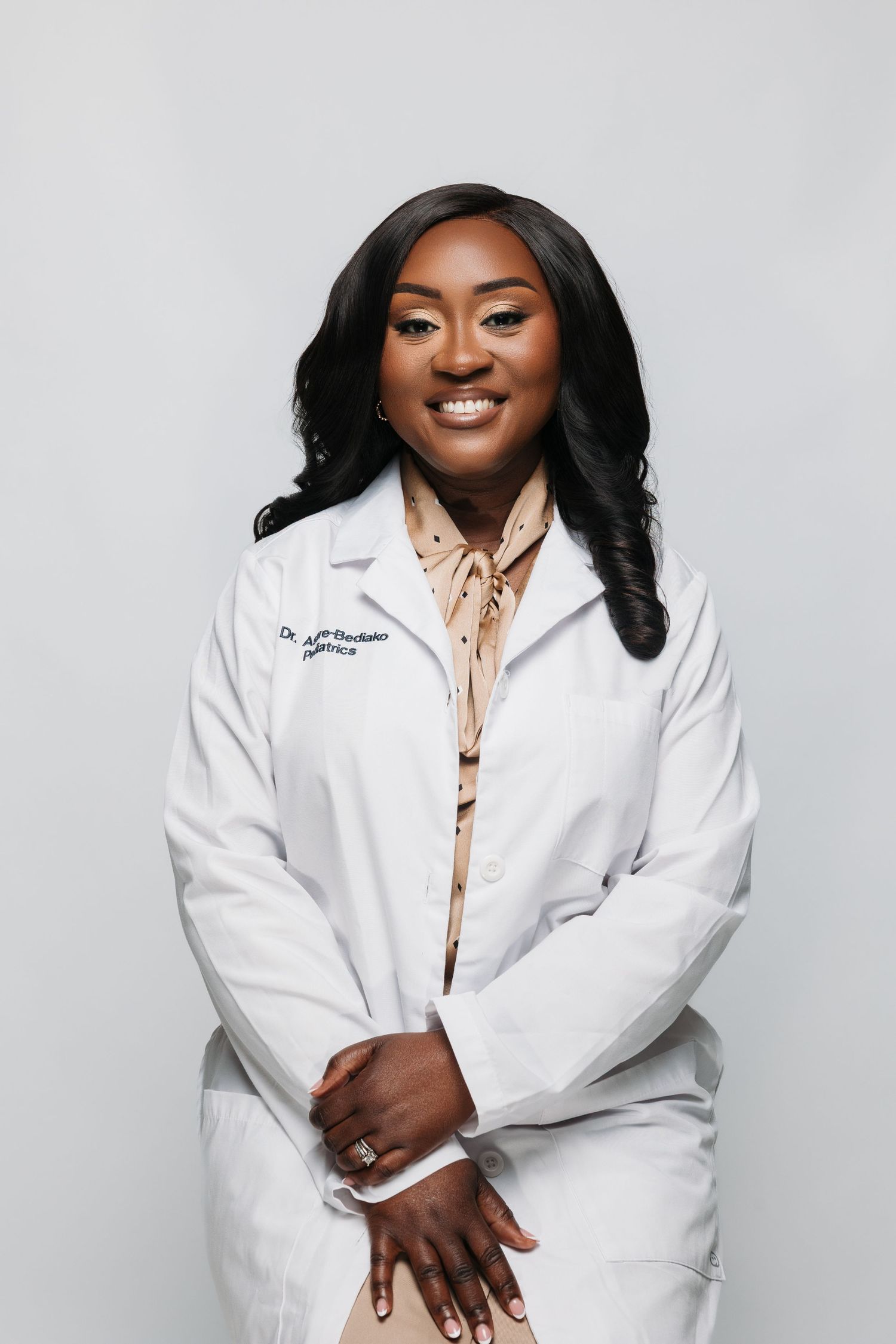 Medical professional in white coat smiling warmly during professional headshot photo session.