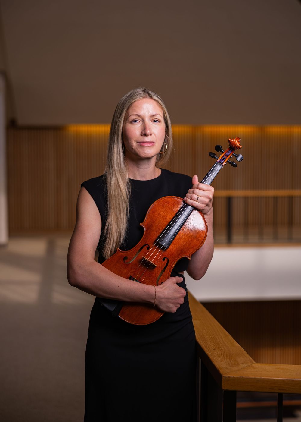 Lady in a black dress posing with her viola for a professional music headshot