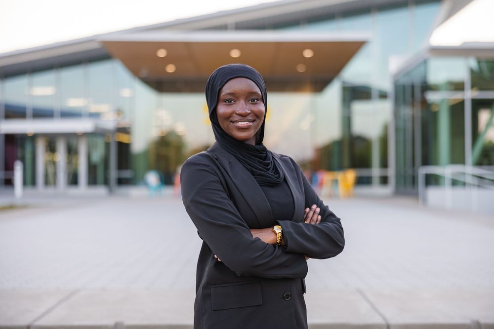 Girl in professional black outfit posing in front of the Siebel Center of Design at UIUC