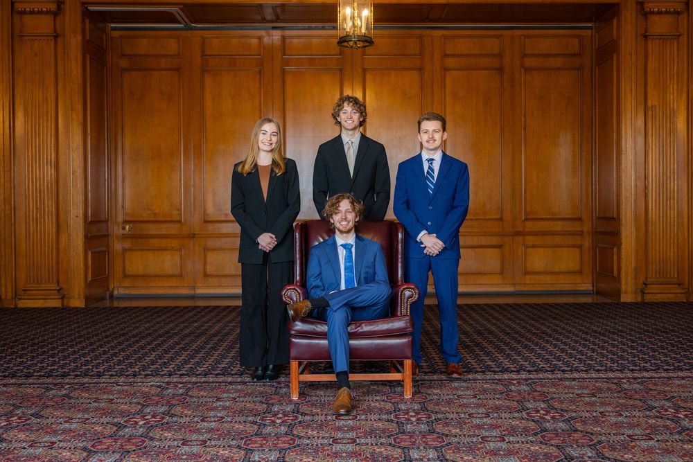 Group of four university students in suits posed for a professional picture in the Illini Union ballroom