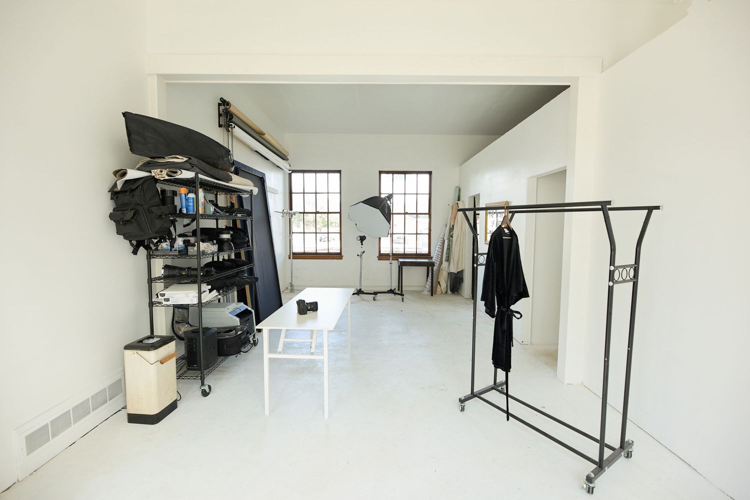 Long empty white studio space with high ceilings and industrial windows.