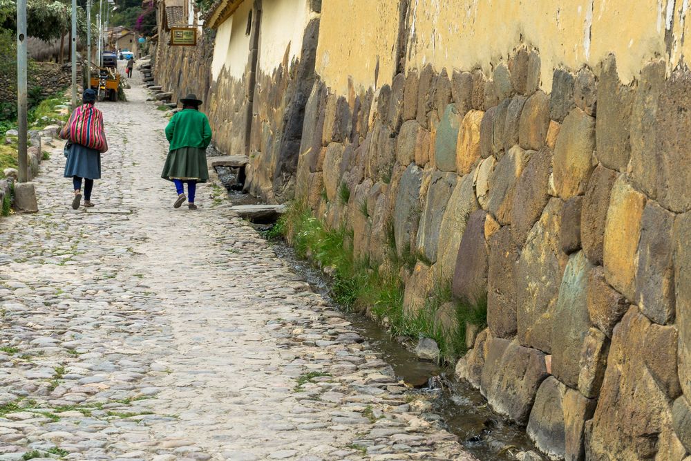 Stone-paved pathway winding between weathered walls in an ancient Incan settlement.