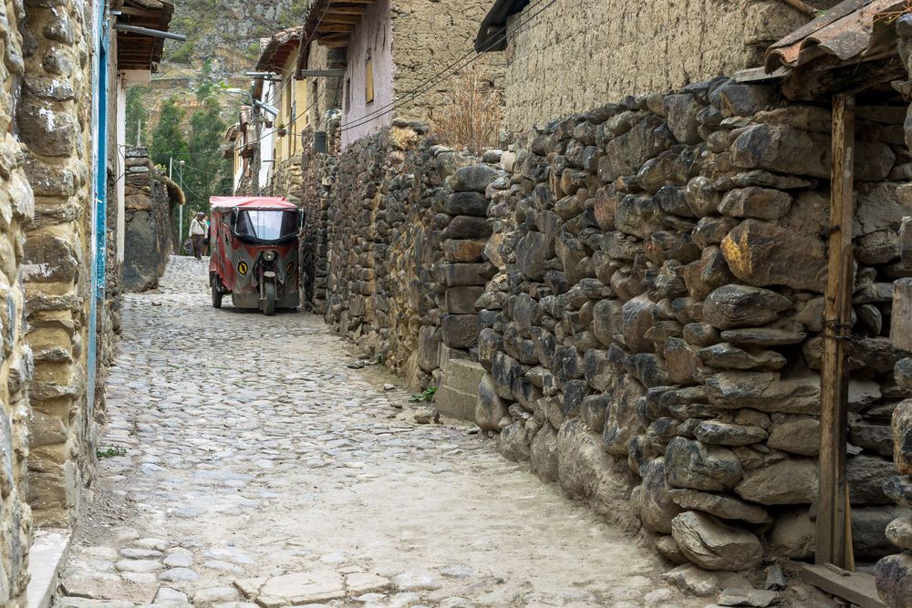 Cobblestone path winding through rustic stone walls in a charming medieval village street.
