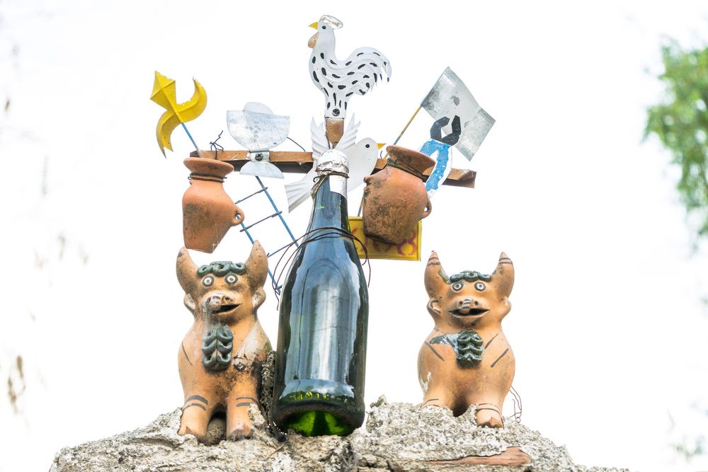 Line of ceramic teddy bear statues wearing sunglasses sit on a white ledge with bottles in a decorative display.