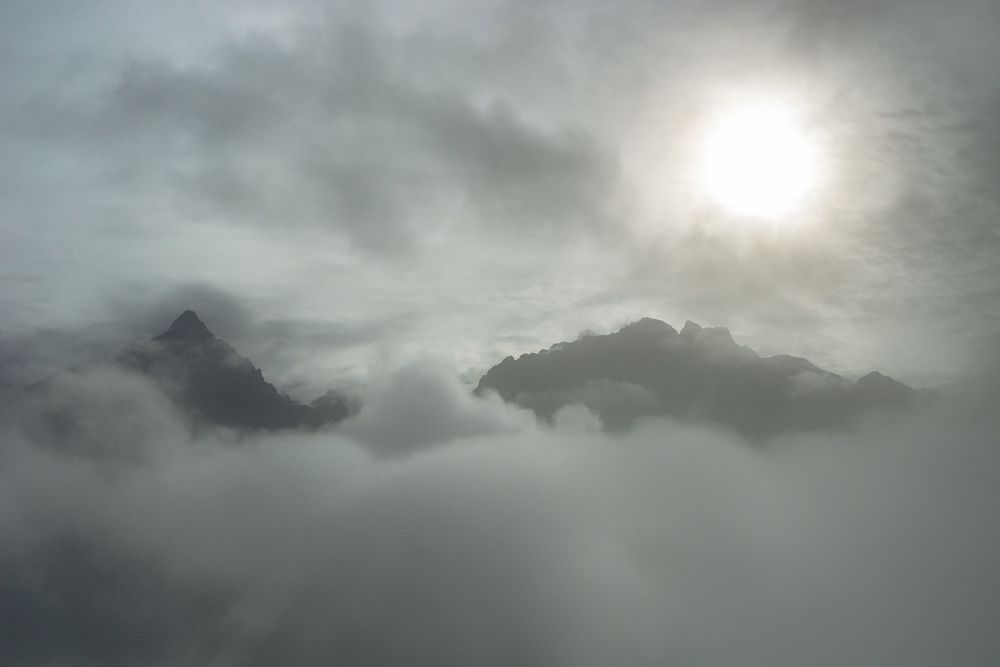 Dramatic cloudy skies with bright sunlight peeking through dark storm clouds creating moody atmospheric scenery.
