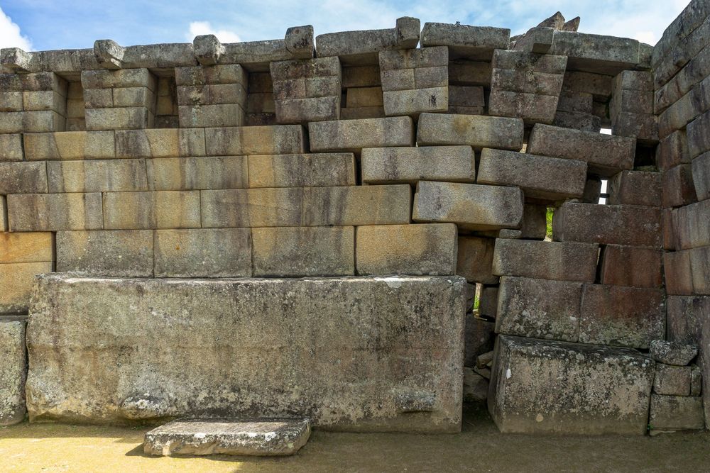 A panoramic view of ancient stone walls and ruins at an archaeological site with partially preserved stone blocks.