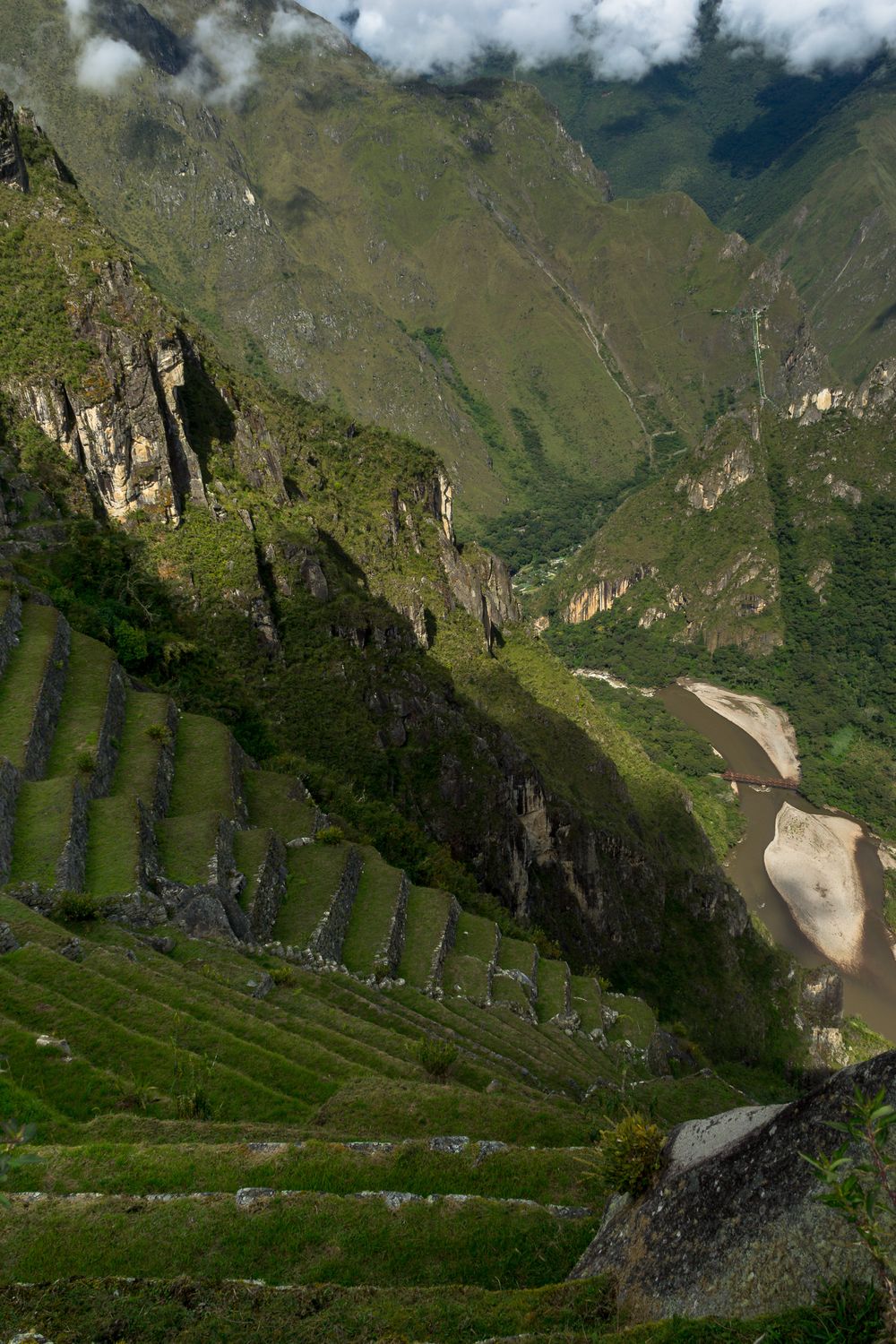 Ancient Inca terraces and winding mountain roads curve through the dramatic landscape of Machu Picchu, Peru.