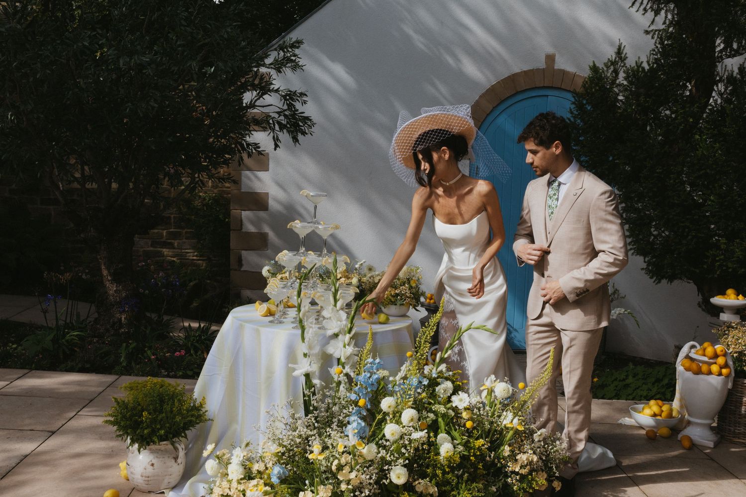 Historic stone mansion with guests gathered on the sprawling lawn under blue skies.