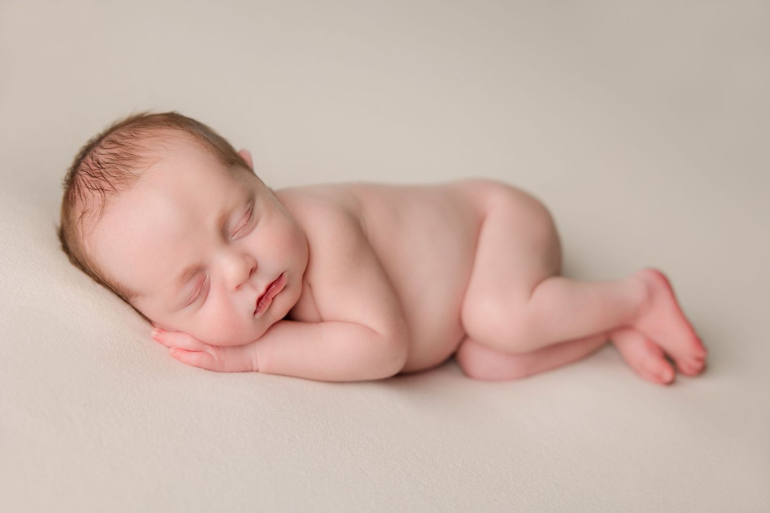 Collection of artistic newborn baby photographs captured in minimalist style on neutral beige backdrop.