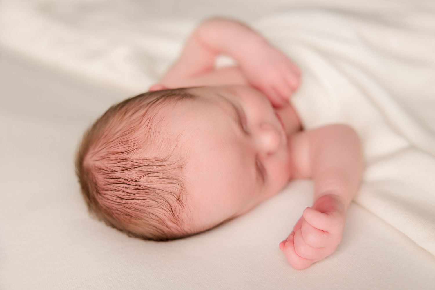 A collage of sweet newborn photos showing tiny closed eyes, delicate fingers, and soft pink skin against white fabric.