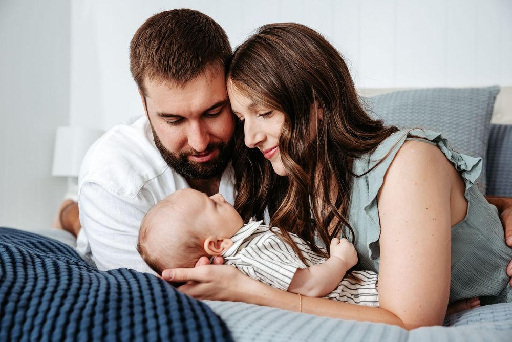 Family relaxing together on white bedding in a cozy bedroom setting.