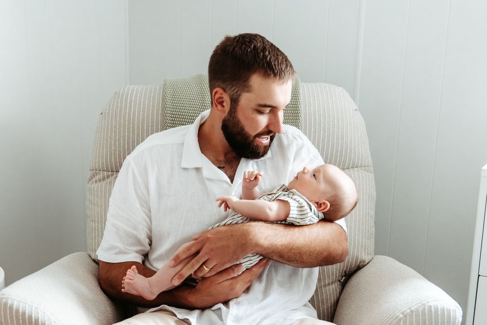 Sweet parenting moments captured in a minimalist white interior setting showing nurturing interactions.