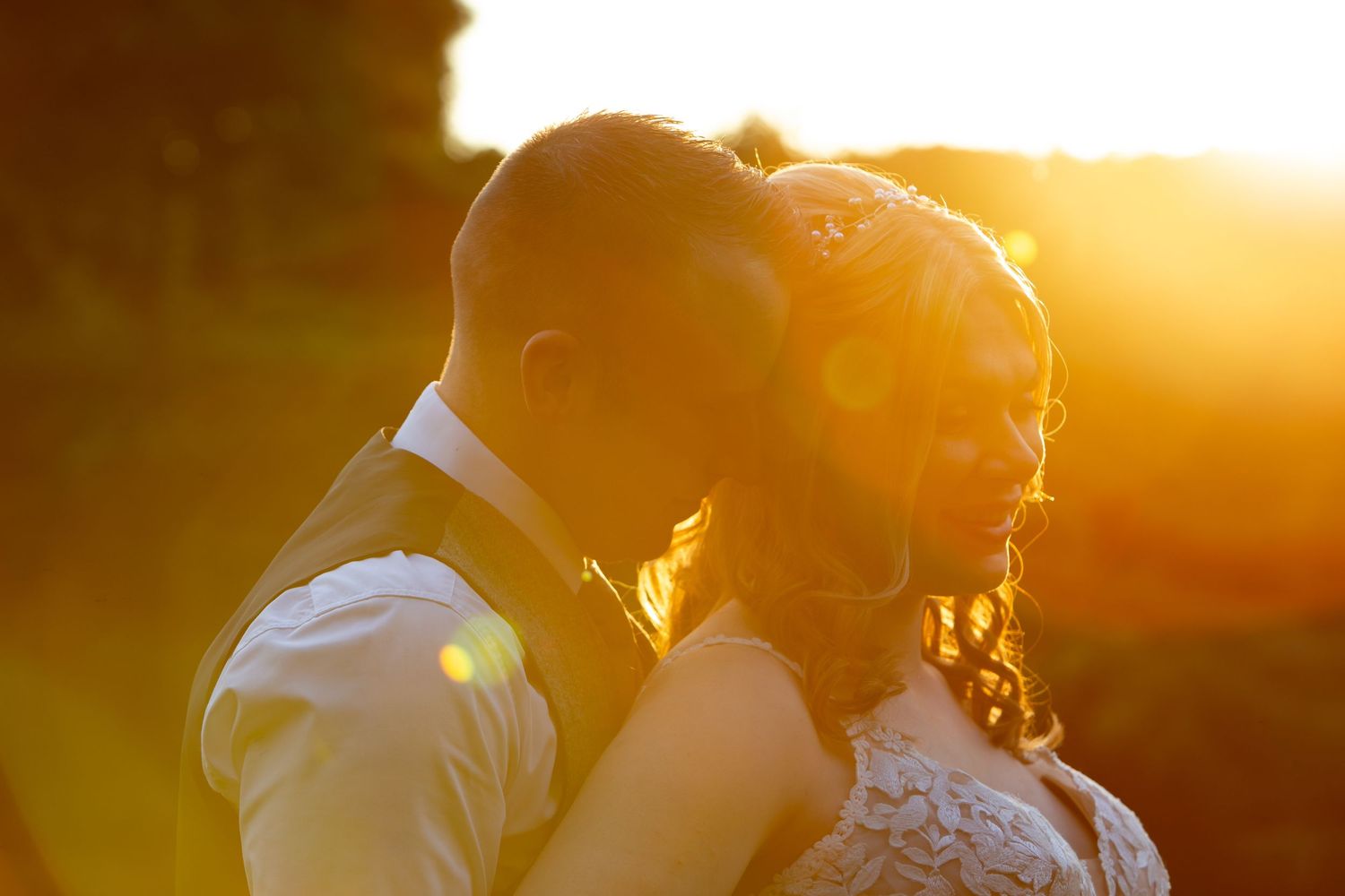 A couple embraces in a romantic golden sunset creating a silhouette against the warm glowing sky.
