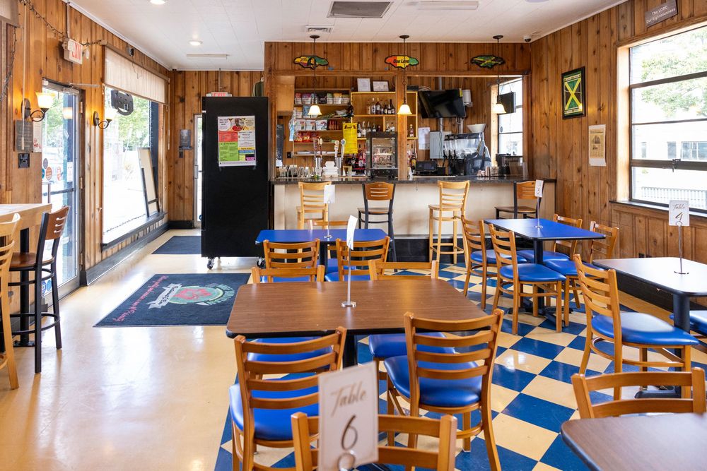 Panoramic view of a cozy, wood-paneled tavern interior with wooden tables and blue chairs in natural lighting.