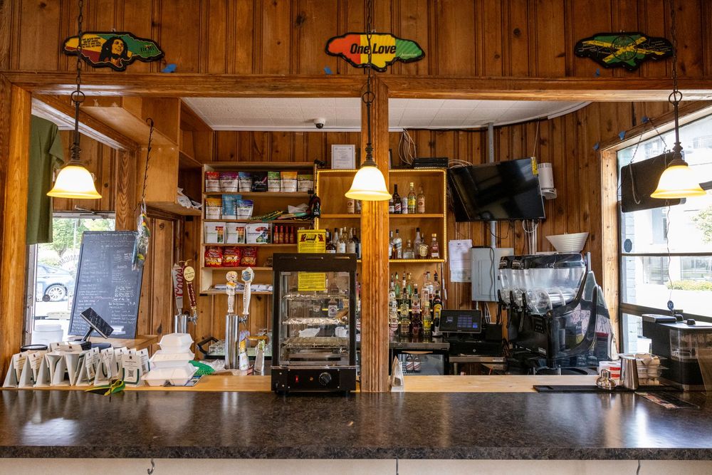 Panoramic view of a rustic wooden bar interior with stools, bottles, and warm lighting creating a cozy atmosphere.