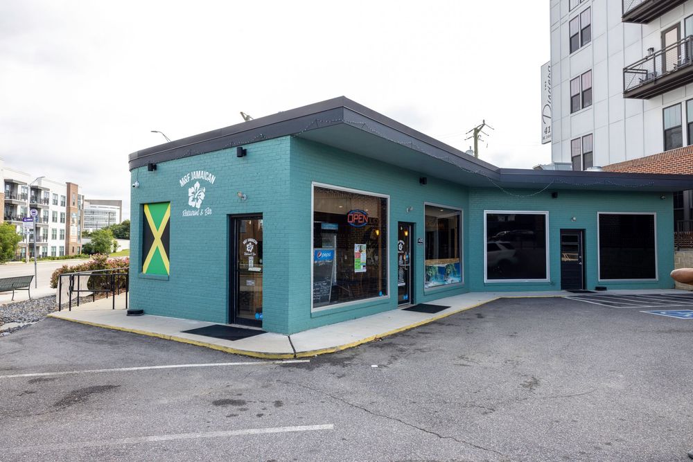 A small turquoise-colored commercial building with a Jamaican flag painted on the exterior.