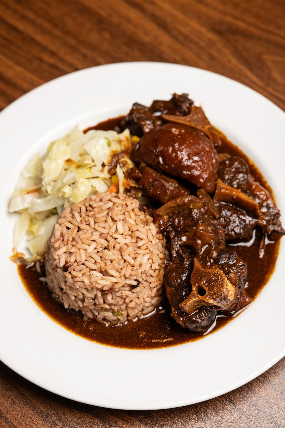 Four images of rice with mushroom and beef stew served on white plates against a wooden table surface.