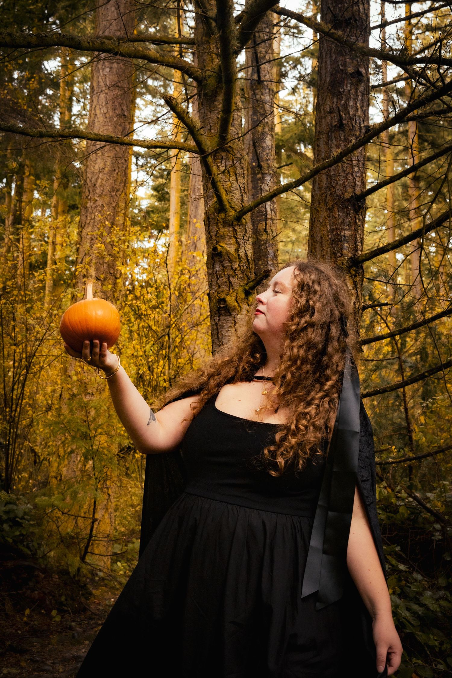Woman holding pumpkin in the forest.