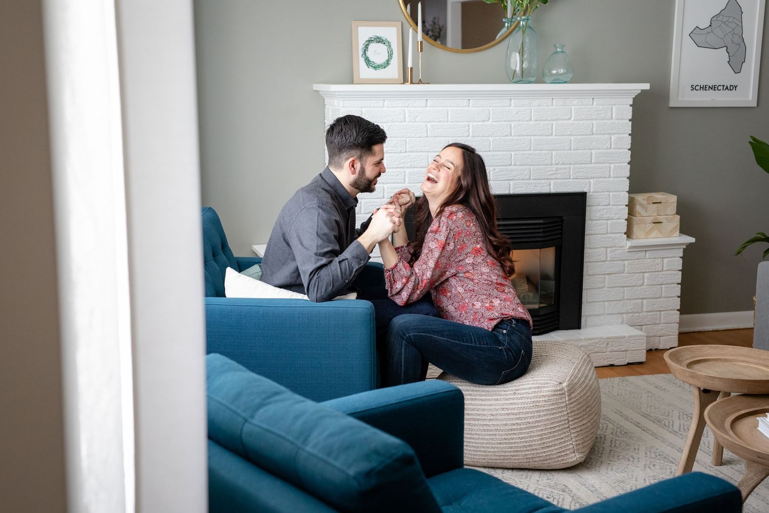 Happy couple laughing together by fireplace in cozy modern living room.