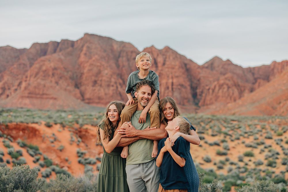 Family of five posing together in front of red rock canyon landscape in the desert Southwest.