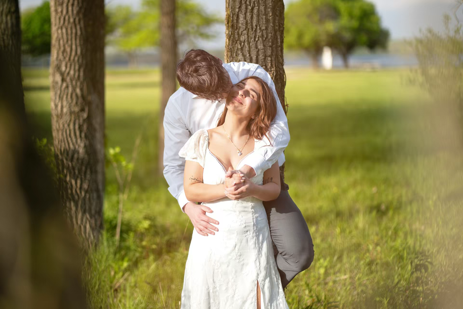 Couple embracing romantically among trees in a sunlit park, at Alum Creek Beach Engagement Photos