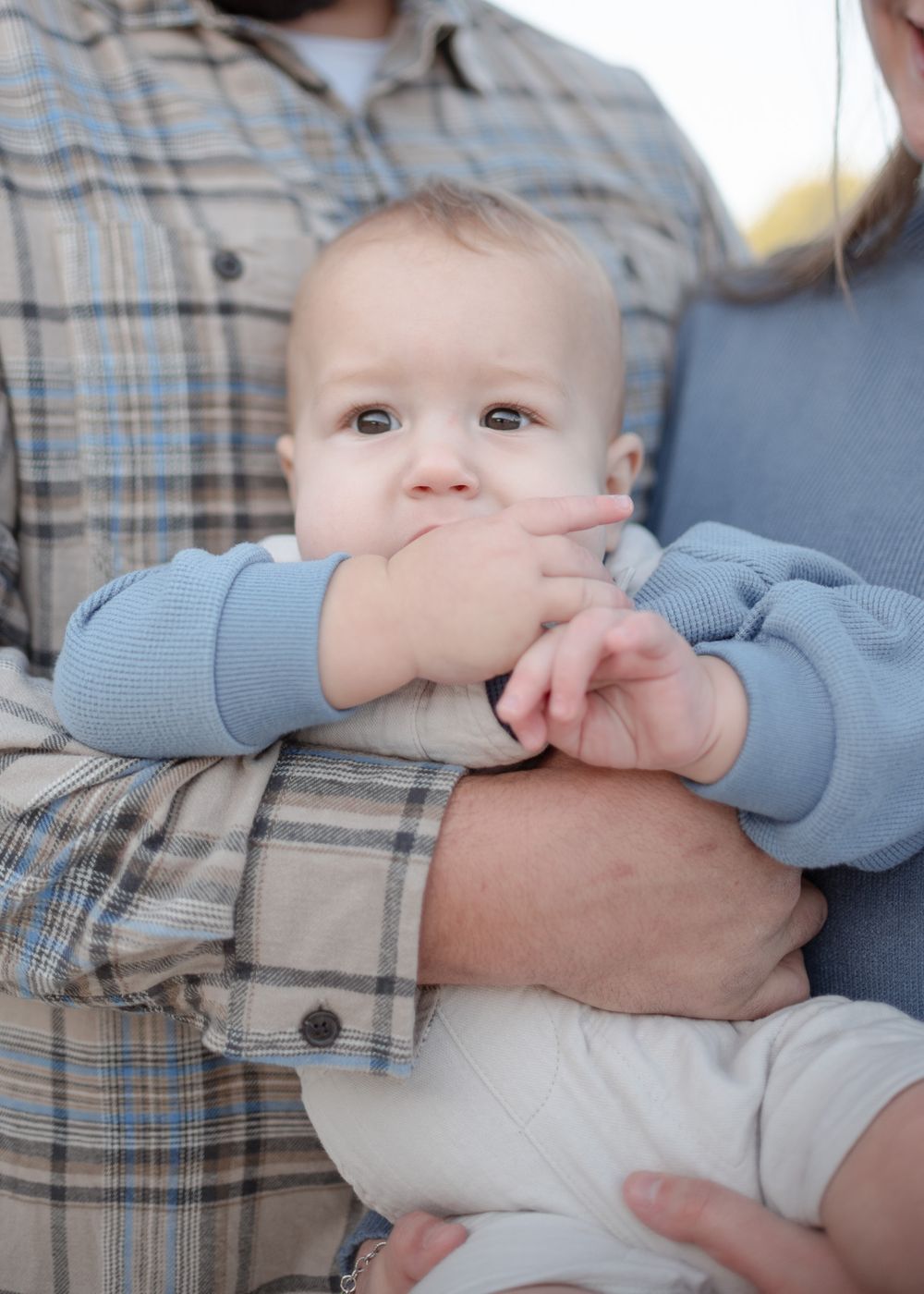 Close-up of baby boy in father’s arms during outdoor family photoshoot in Temple Texas with soft natural light