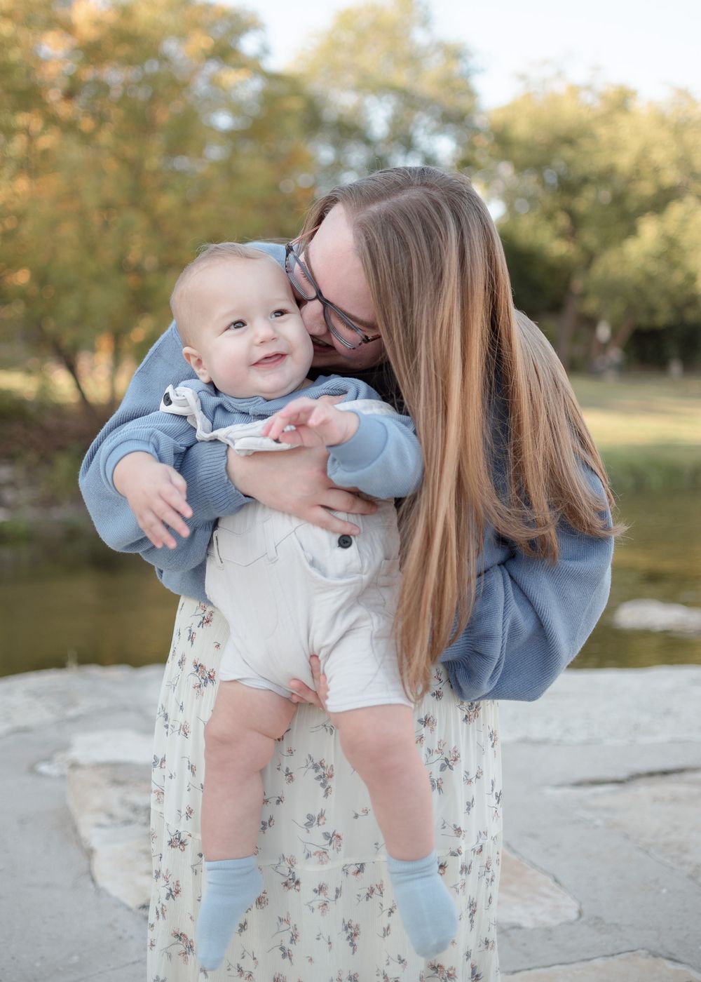 Mother holding and smiling at baby boy during outdoor family session in Temple Texas at Nolan Creek