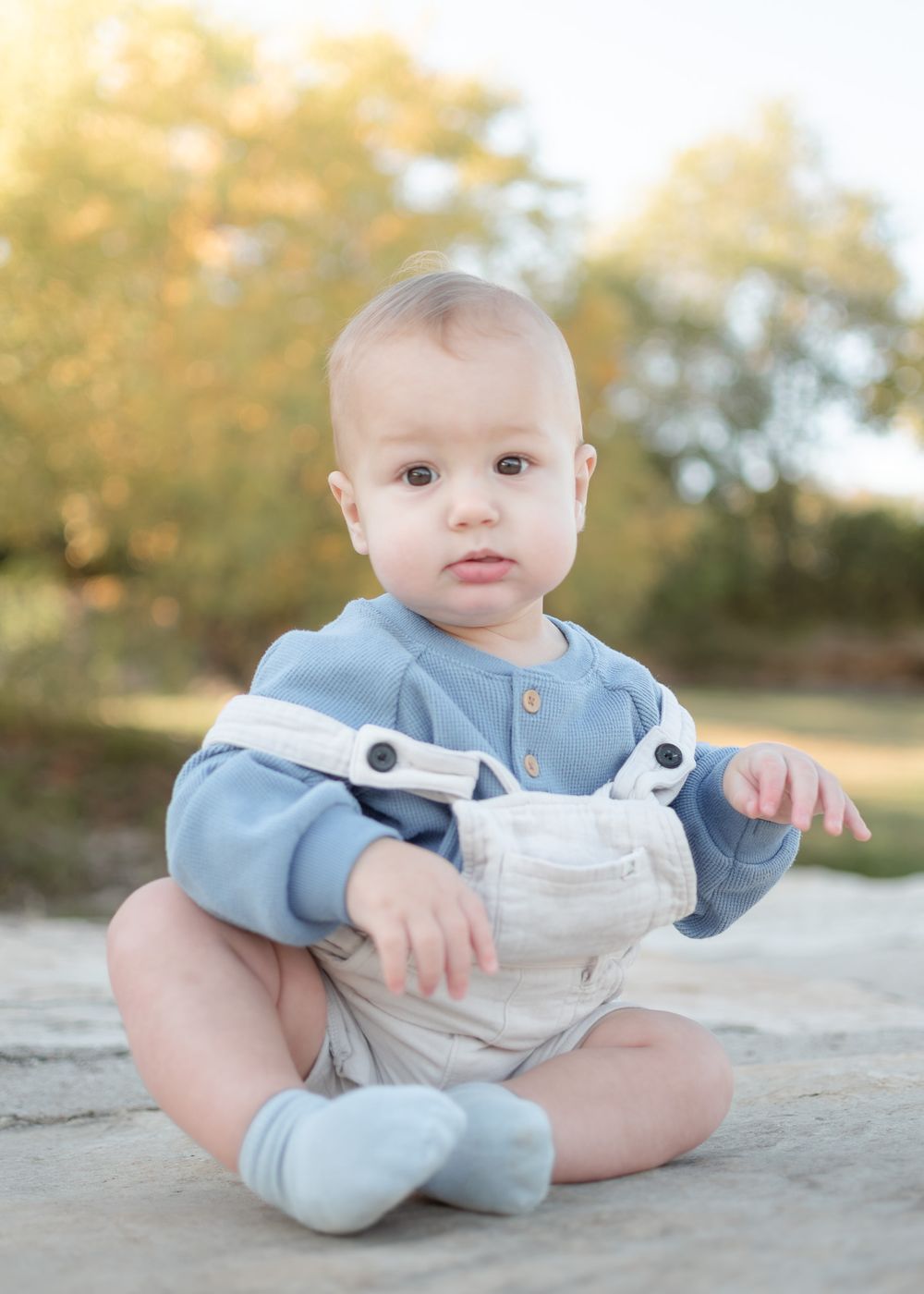 Baby milestone portrait of infant sitting outdoors in Temple Texas with soft golden light and natural background