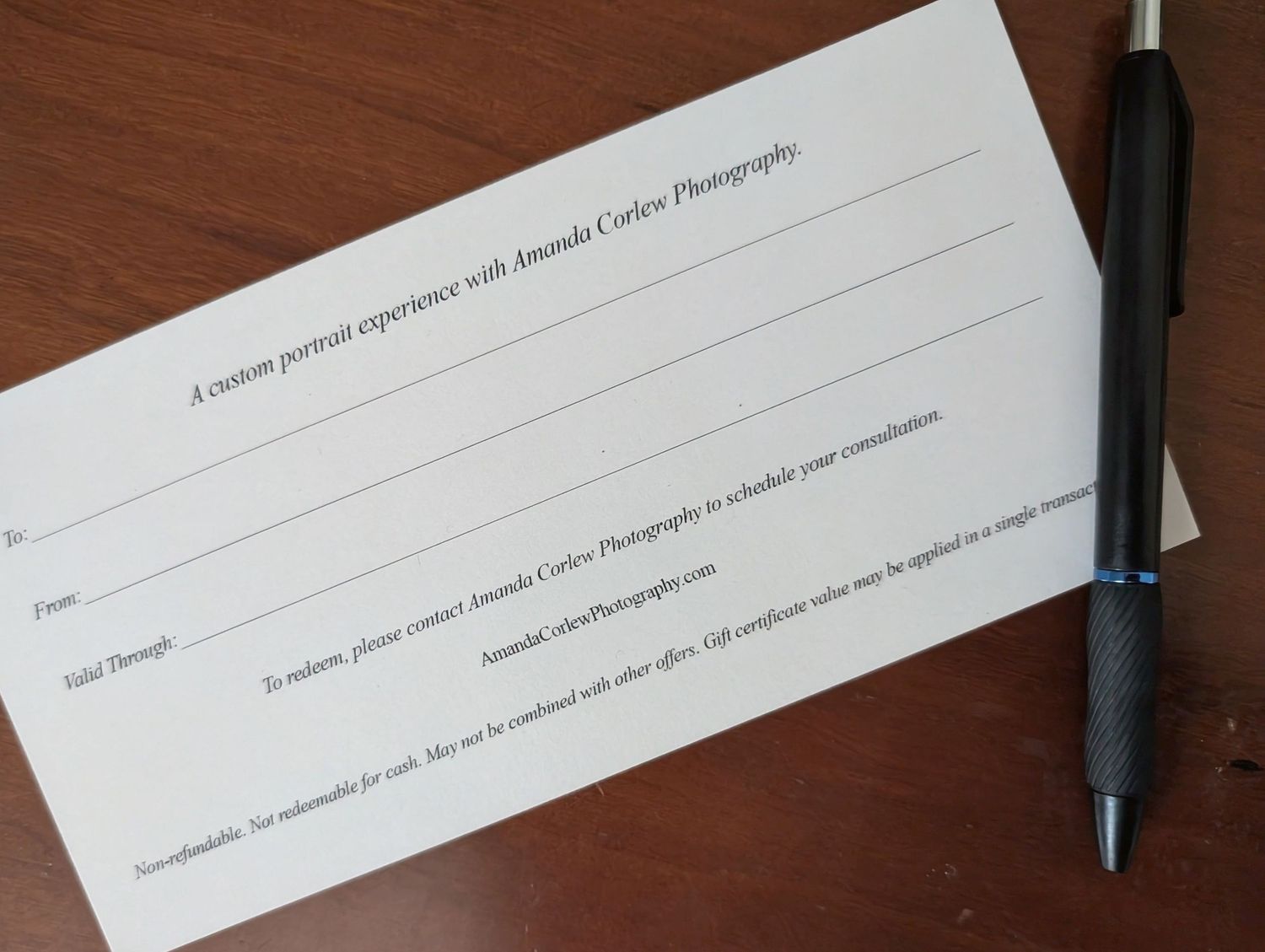 Gift certificate for Amanda Corley Photography custom portrait experience, with a black pen on a wooden desk.