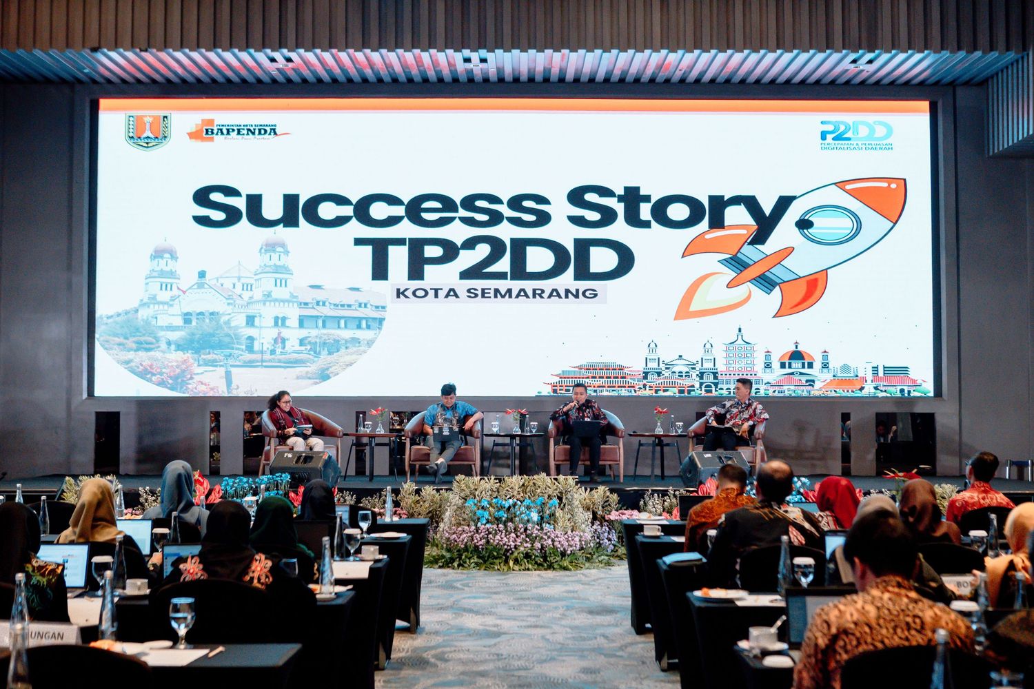 Success Story TP2DD Kota Semarang event presentation on stage with panelists and audience in a conference hall.