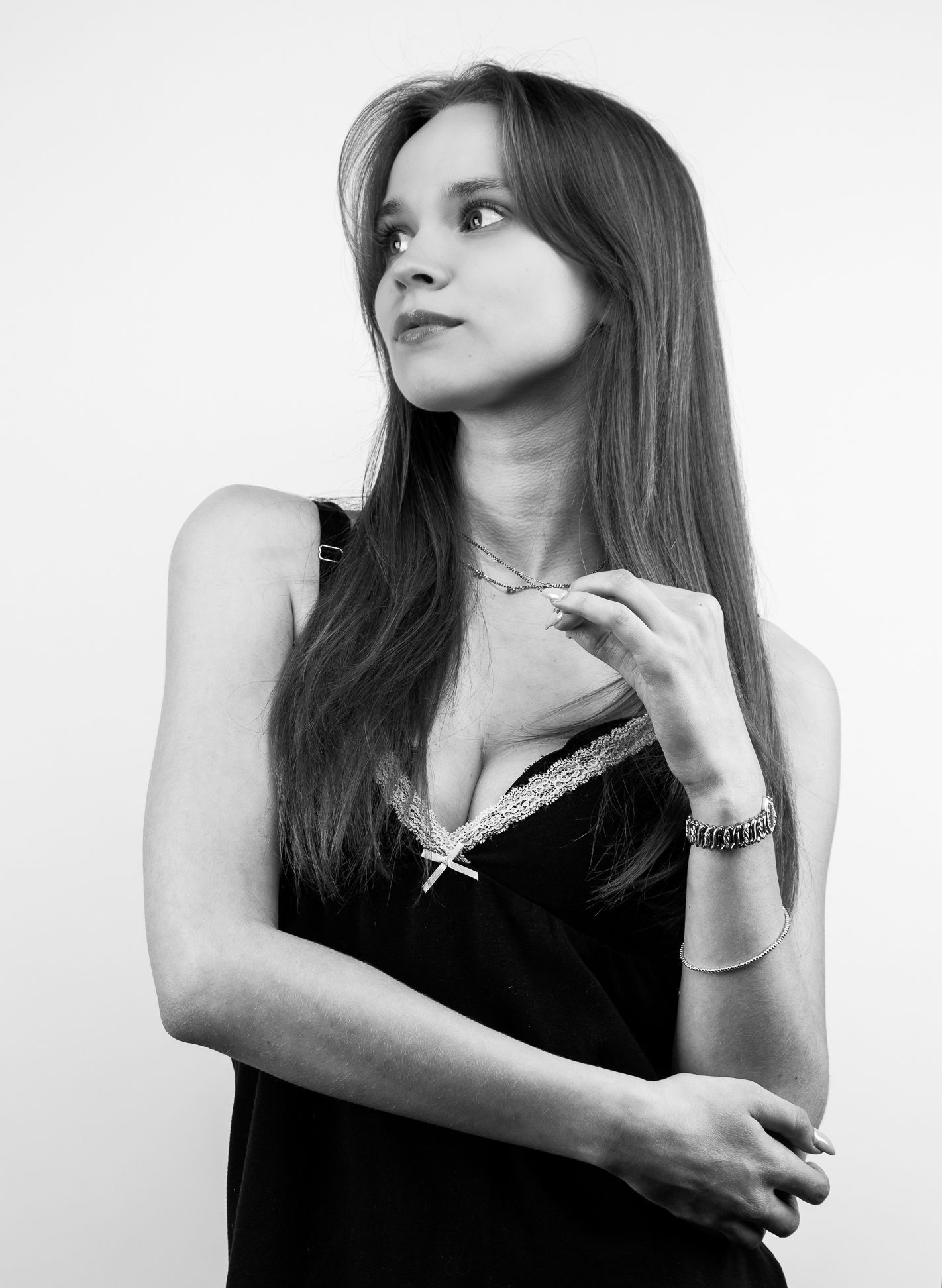 Black and white image of a girl in a black tank top, with arms up, looking up to the left