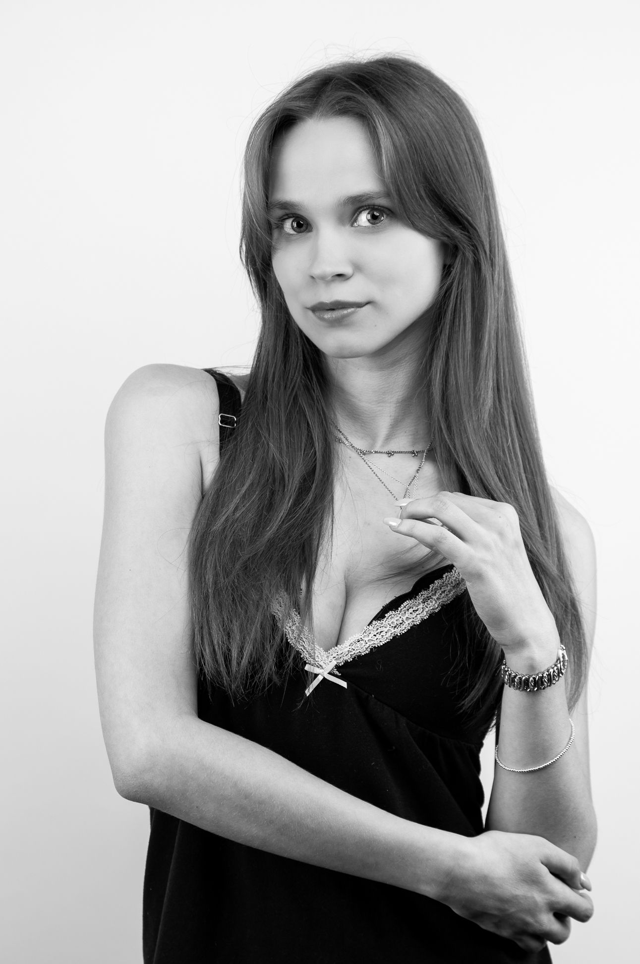 Black and white image of a girl in a black tank top, arms up in front of her chest, looking forward