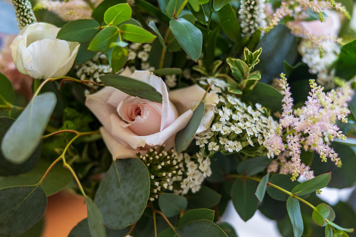 Close-up of a elegant wedding bouquet featuring blush roses, white blooms, and eucalyptus greenery.