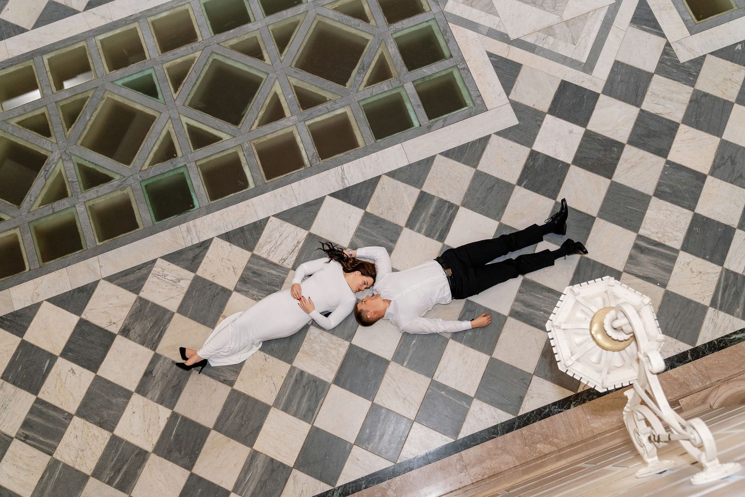 Couple sharing a romantic kiss inside an ornate gold elevator, bride in white gown, groom in dark suit.